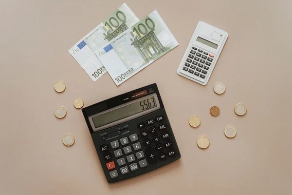 Calculatrice et pièces en euros illustrant la vérification du seuil de dépôt de 20 euros